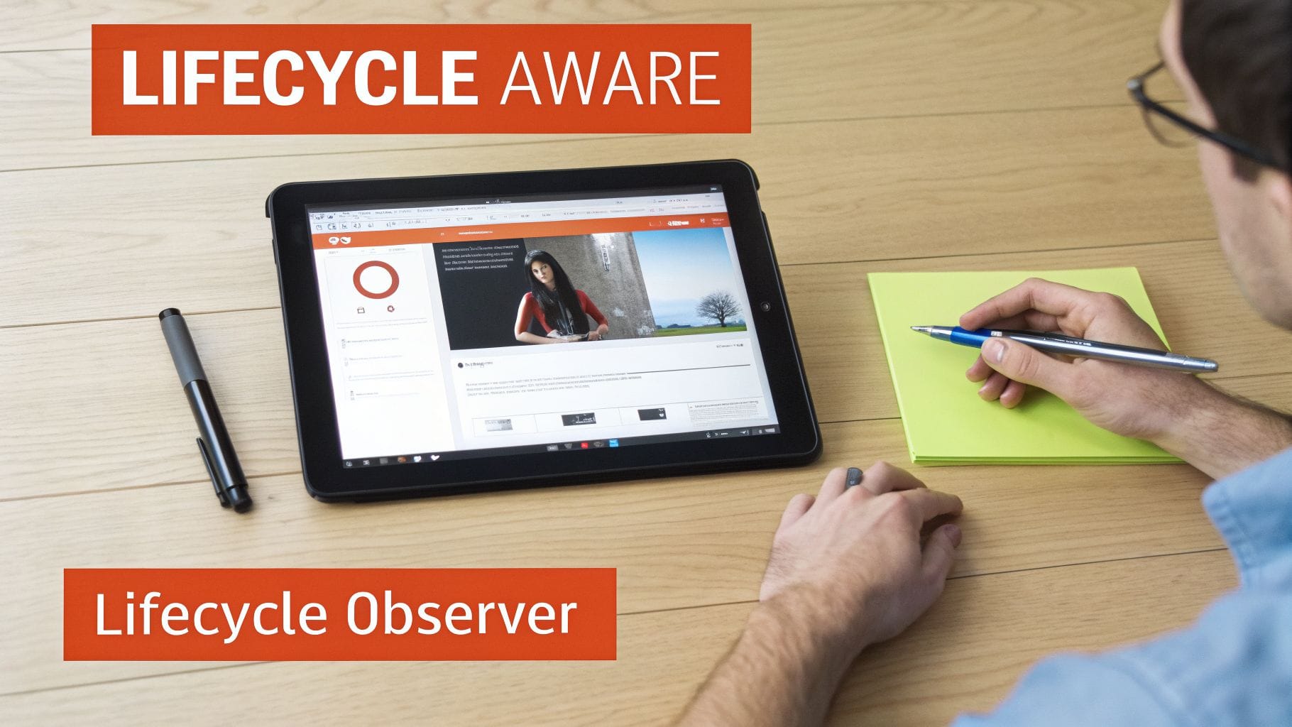 Person writing notes and interacting with a tablet displaying a webpage on a wooden desk, emphasizing lifecycle concepts.